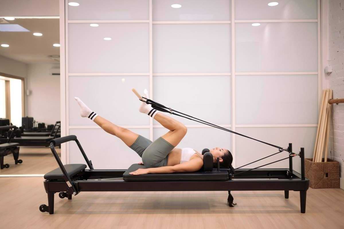 Frau führt eine Übung auf Reformer Gerät durch Symbolbild.jpeg