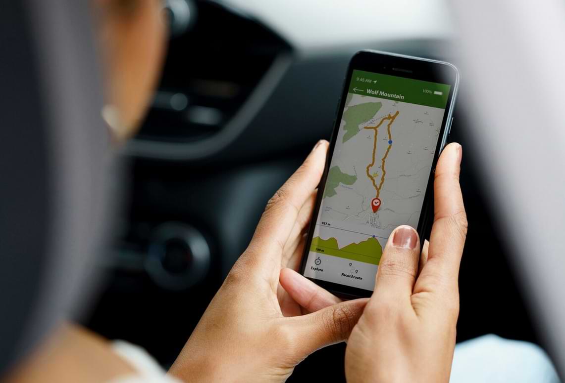 frau im auto verfolgt tracking route im smartphone mit karten app.jpg