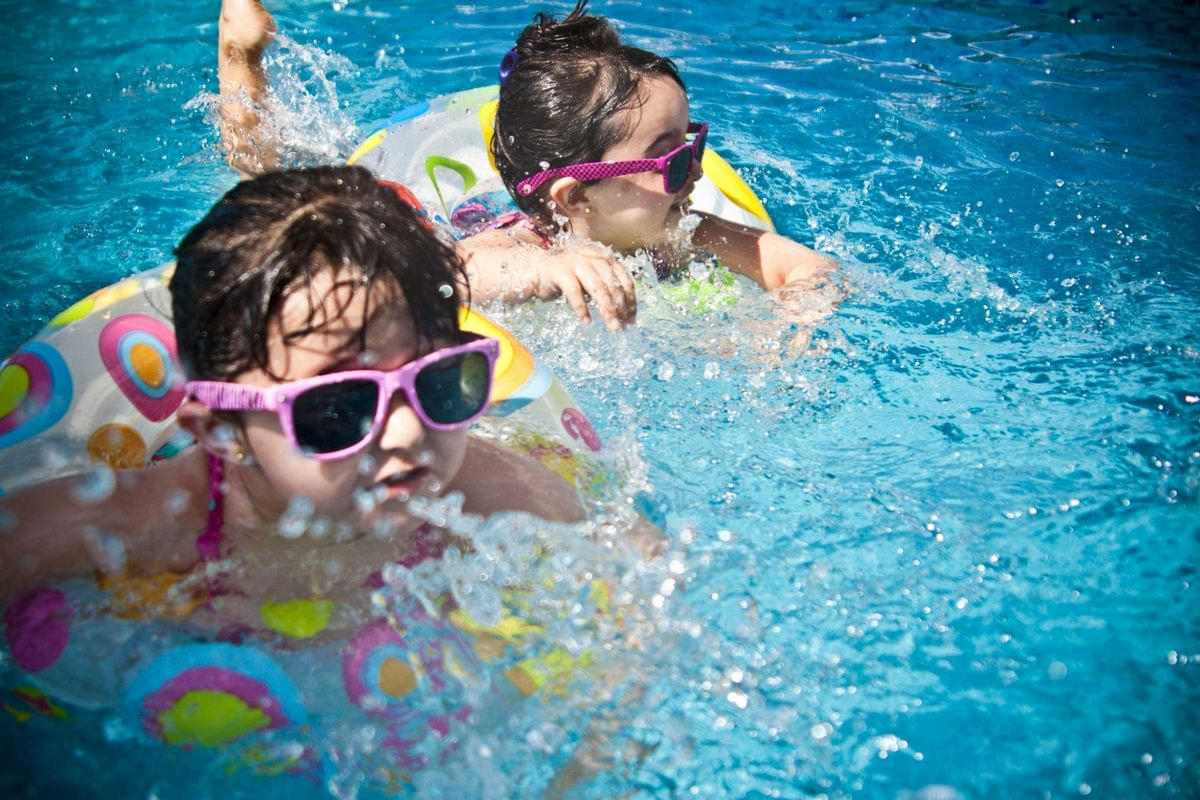 kinder mit sonnenbrille und schwimmreifen im pool.jpg