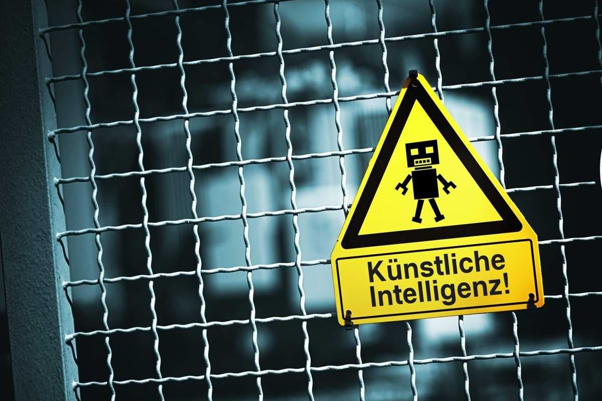 Symbolbild Roboterfigur auf einem Warnschild mit Aufschrift Künstliche Intelligenz.jpeg
