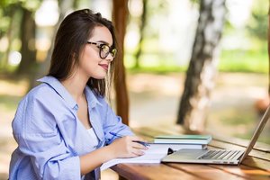 selbstbewusste selbständige frau mit brille arbeitet im freien am notebook.jpg